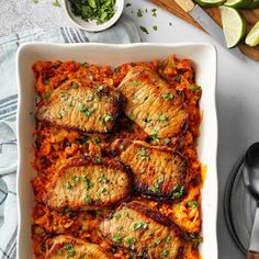 meat and rice casserole in a white dish with limes on the side