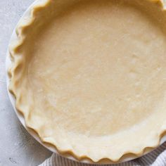 an uncooked pie crust sits on top of a white table cloth next to a knife