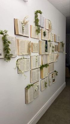 several open books are hung on the wall with plants growing out of them and attached to it