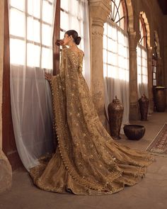 a woman in a golden dress leaning against a wall