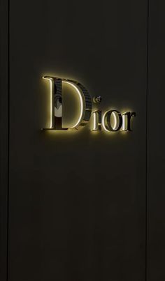 the logo for dior is illuminated in gold on a black background with white lettering