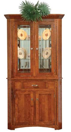 a wooden china cabinet with glass doors and two plants on top of the hutch