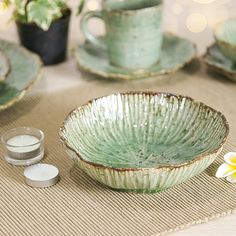 a table topped with green dishes and cups