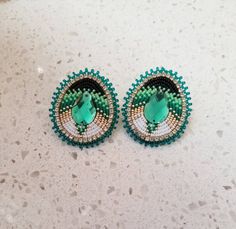 two green and white beaded earrings sitting on top of a marble counter next to each other