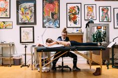 a woman getting a back massage from a man in a room with art on the walls