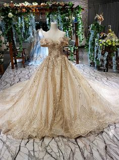 a dress is on display in a room full of flowers and greenery, with an archway behind it