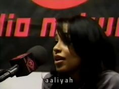 a woman talking into a microphone in front of a red and black sign with the words revolution on it