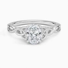 a white gold ring with a oval shaped diamond in the center and an intricate band around it