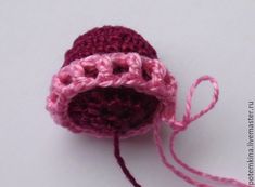 a crocheted pink and red object on a white surface with a string attached to it