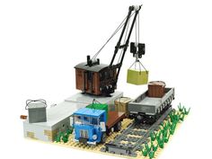 a lego model of a crane lifting cargo on top of a train car and trailer