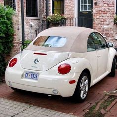 a white car parked in front of a brick building next to a green planter