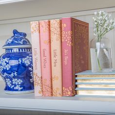 some books and vases are sitting on a shelf next to each other with flowers in them