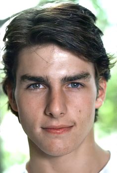 a close up of a person wearing a white shirt with trees in the back ground