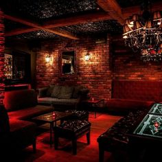 a living room filled with furniture and a table in front of a brick wall that has lights on it