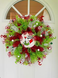 a christmas wreath on the front door with green and red mesh around it, decorated with an image of dr seuss's hat