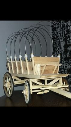 a wooden wagon with four wheels and six bottles in the back, sitting on a table