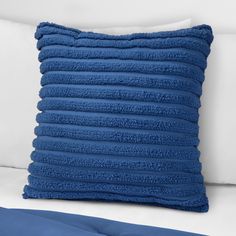 a blue throw pillow on top of a white bed