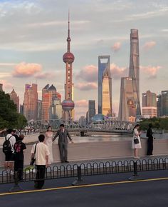 people are standing on the edge of a bridge looking at the cityscape in the distance