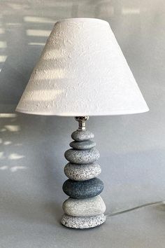 a lamp that is sitting on top of a stone stack with a white shade over it