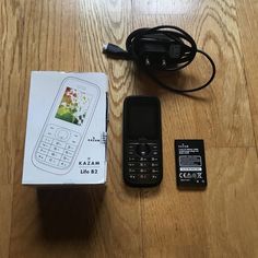 an old cell phone sitting on top of a wooden floor next to a charger