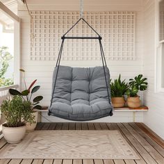 a hanging chair on a porch with potted plants