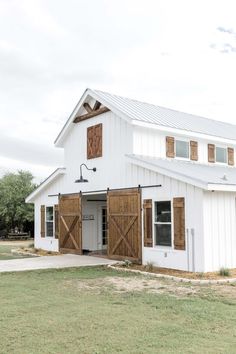 a white barn with wooden doors and windows