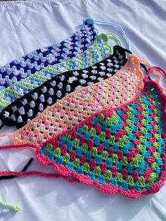 three crocheted bags sitting on top of a white sheet