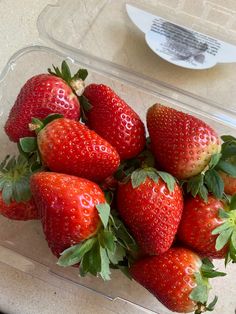 a plastic container filled with lots of ripe strawberries