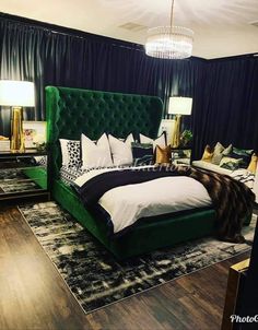 a green velvet bed in a bedroom with black drapes and white pillows on the headboard