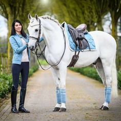 a woman standing next to a white horse