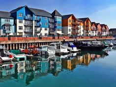 many boats are docked in the water near some buildings