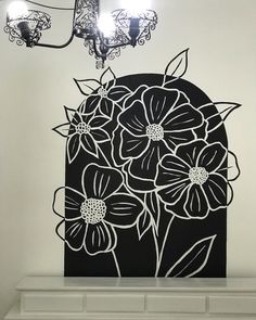 a black and white painting on the wall with lights hanging above it in a room