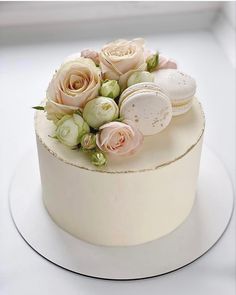 there is a white cake with pink flowers on the top and two macaroons in the middle