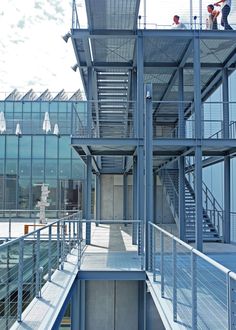 three people standing on top of a building with metal railings and balconies