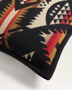 a close up of a black and red pillow on a white surface with an animal design