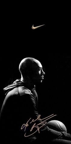 a man sitting in front of a black background with a yellow nike logo on it