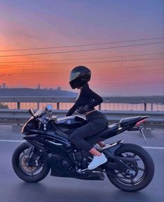 a person riding on the back of a motorcycle down a road at sunset with power lines in the background