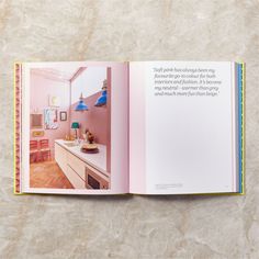 an open book with pink walls and wood flooring on top of a white counter