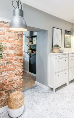 a kitchen with brick wall and white cabinets in the center, along with an open door leading to another room