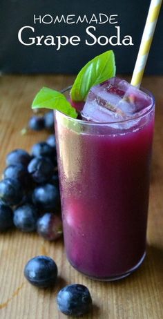 a glass filled with purple soda next to blueberries