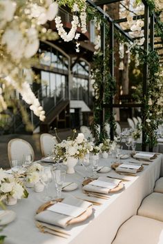 the table is set with white flowers and place settings for an elegant dinner or reception