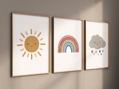 three framed pictures hang on the wall next to each other, one with a sun and rainbow