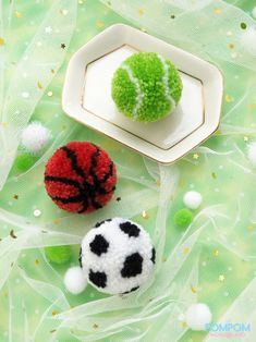 two small crocheted balls sitting next to each other on a green table cloth