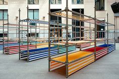 an outdoor area with multiple colored benches in front of a building