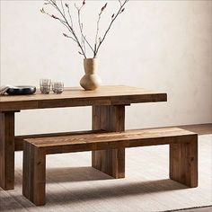 a wooden table with two benches in front of it and a vase filled with flowers