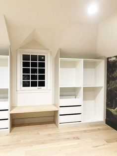 an empty room with white bookcases and shelves on the wall, in front of a painting