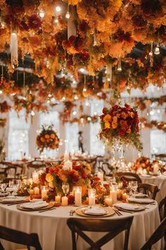 a table with candles and flowers hanging from the ceiling is set for an elegant dinner