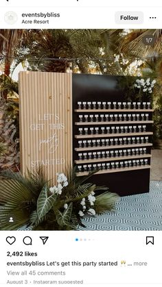 a black and white sign sitting on top of a table next to palm trees with writing on it