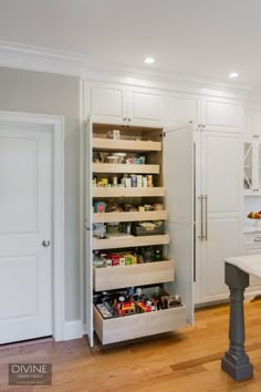 an open pantry in the middle of a kitchen with white cabinets and wood flooring