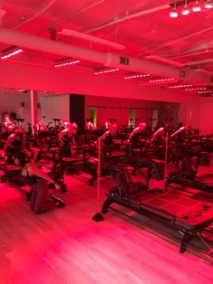 an indoor gym with rows of treadmills and red lights